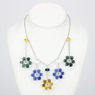 Collier chaine argent 925 avec 5 perles en forme de fleur marguerite de couleur variées, jaune pour celle du milieu puis sur les côtés bleu et grise. Perle fleur transparente. Les perles en verre sont pendantes de part et d'autre de la chaine, tombantes sur le buste. -Atelier horizon verre