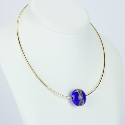 Bijoux . Collier une perle de verre forme lentille de couleur bleu avec incrustation d'une bande de feuille d'or. Monture en argent 925, finition dorée. Travail au chalumeau. Fait main. -Atelier horizon verre