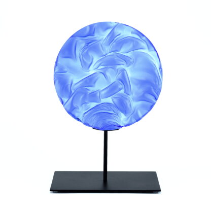 Pièce d'art décoratif de forme circulaire en cristal nommé "Magma" de taille grande (24 cm de diamètre). Objet avec du relief, texturés, avec des effets de drapé. Pièce en cristal de couleur bleu marine sur support en métal thermolaqué noir. Pâte de verre. -Atelier horizon verre