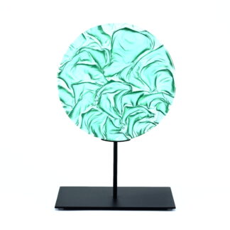 Pièce d'art décoratif de forme circulaire en cristal nommé "Magma" de taille grande (24 cm de diamètre). Objet avec du relief, texturés, avec des effets de drapé. Pièce en cristal de couleur vert menthe sur support en métal thermolaqué noir. Pâte de verre. -Atelier horizon verre