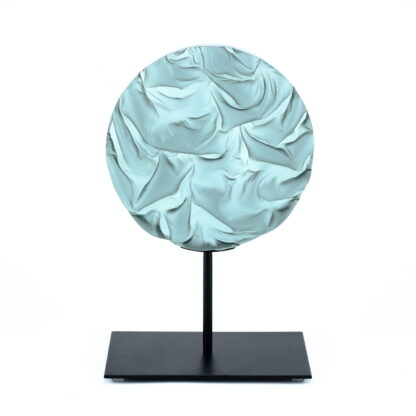 Pièce d'art décoratif de forme circulaire en cristal nommé "Magma" de taille moyenne (18 cm de diamètre). Objet avec du relief, texturés, avec des effets de drapé. Pièce en cristal de couleur gris sur support en métal thermolaqué noir. Pâte de verre. -Atelier horizon verre