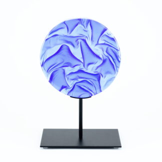 Pièce d'art décoratif de forme circulaire en cristal nommé "Magma" de taille moyenne (18 cm de diamètre). Objet avec du relief, texturés, avec des effets de drapé. Pièce en cristal de couleur bleu marine sur support en métal thermolaqué noir. Pâte de verre. -Atelier horizon verre