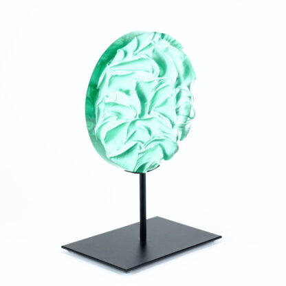 Pièce d'art décoratif de forme circulaire en cristal nommé "Magma" de taille moyenne (18 cm de diamètre). Objet avec du relief, texturés, avec des effets de drapé. Pièce en cristal de couleur vert menthe sur support en métal thermolaqué noir. Pâte de verre. -Atelier horizon verre